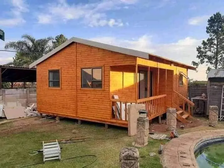 Compact wooden lodge under construction beside a garden